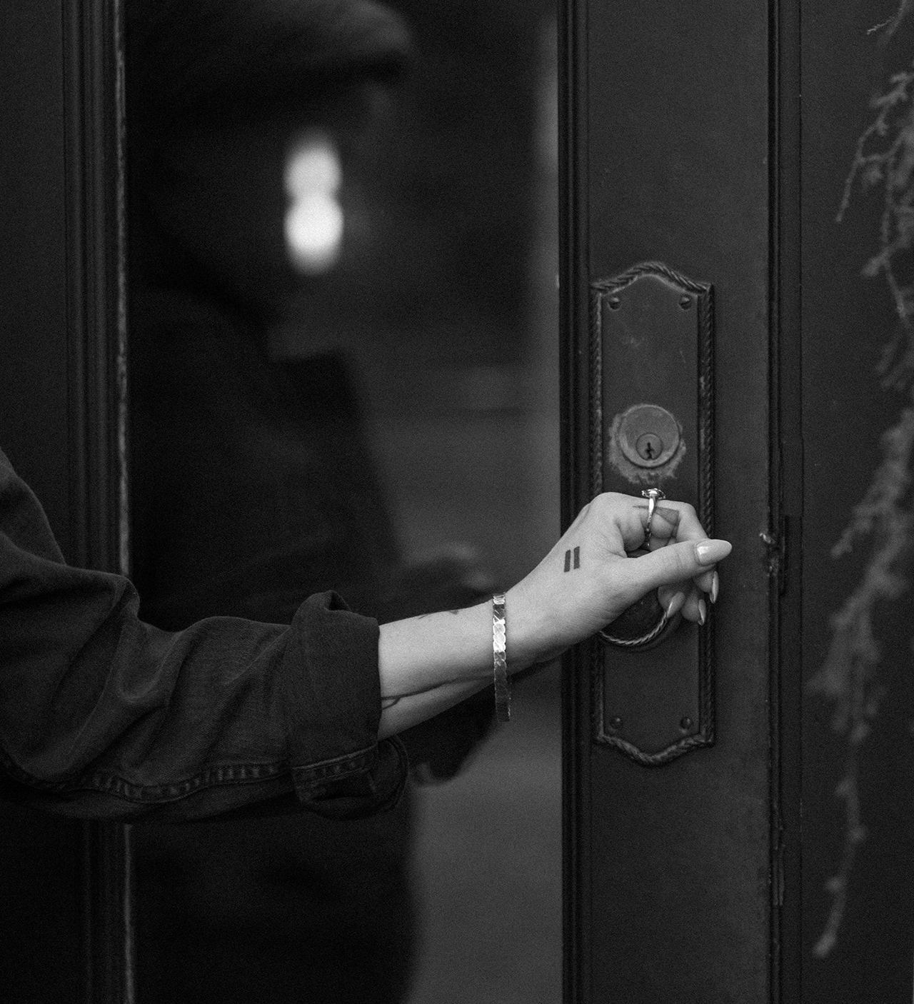 A hand reaching for the handle of a dark, unmarked door